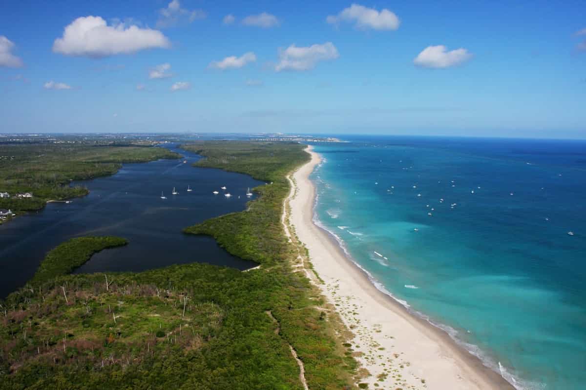An aerial view of Hutchinson Island, where the Atlantic Ocean meets St Lucie Inlet, showcasing the beautiful coastline of Martin County, Florida. The image was taken by Martin County Office of Tourism & Marketing and highlights the hidden gem of Hutchinson Island mentioned in the article.